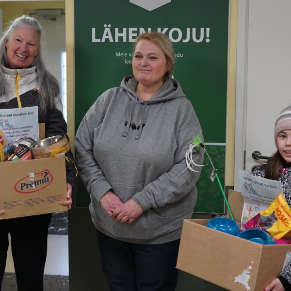 Three people standing infront of a wall with cardboard boxes